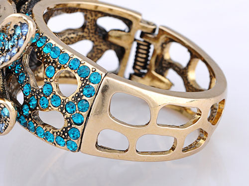 Electrifying Blue Zircon Dragonfly Over A Gold Cuff Bracelet